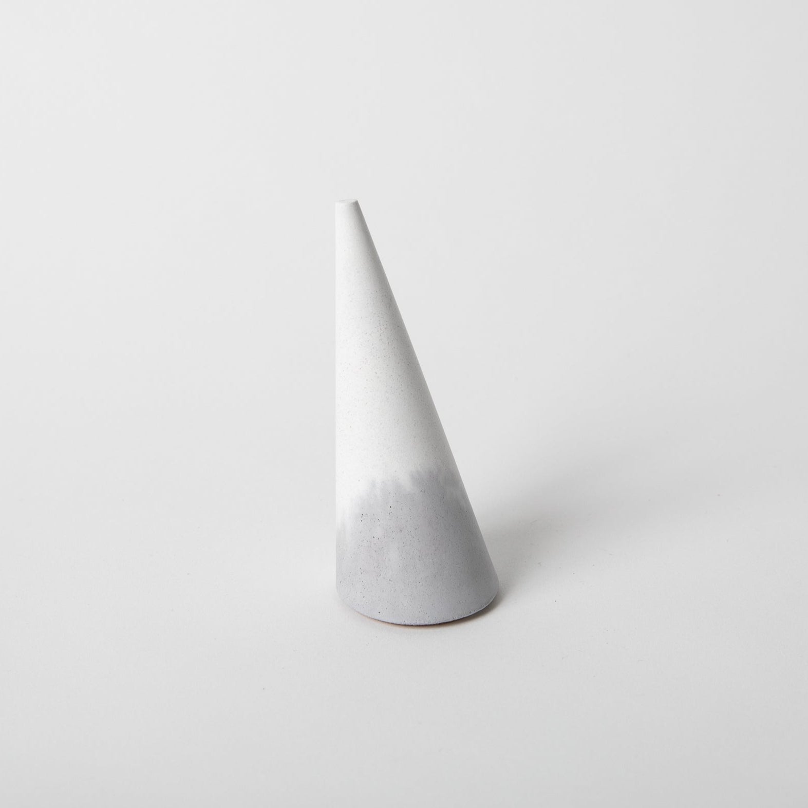 Cone shaped concrete ring holder with cork base in grey and white.
