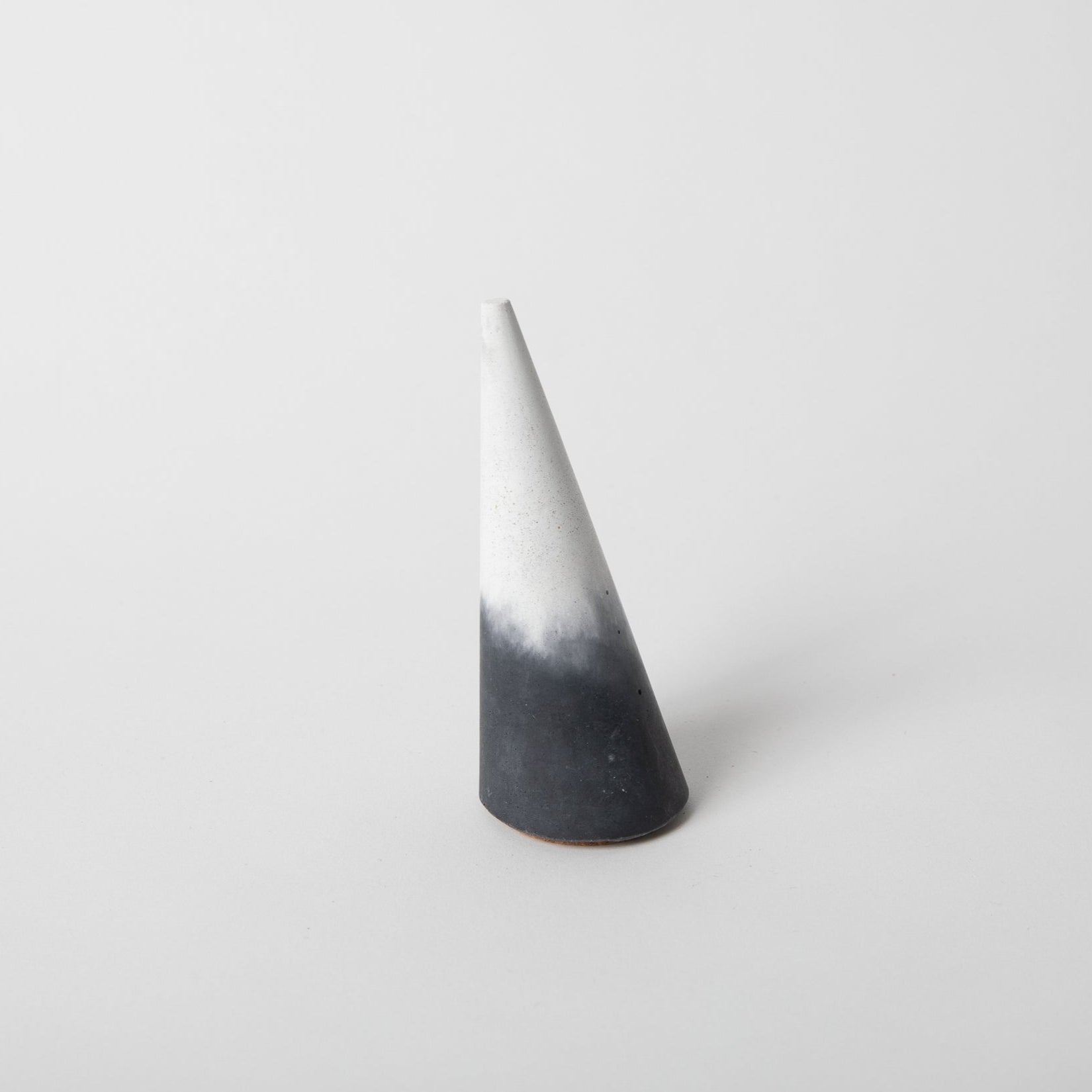 Cone shaped concrete ring holder with cork base in black and white.